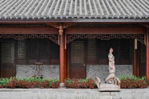 a statue of a woman sitting on a bench in front of a building at Jishang Qingcheng Mt Villa in Dujiangyan