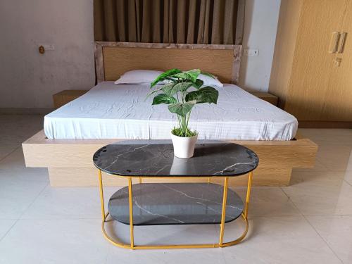 a potted plant on a table next to a bed at Krishna Villa in Kakarmatha