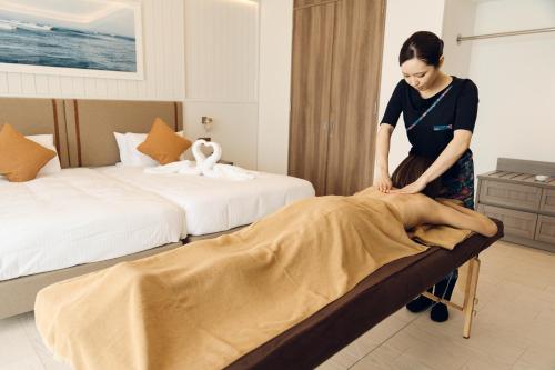 a woman is putting a blanket on a bed at THE SENAGAJIMA STORYLINE in Tomigusuku