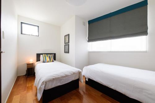 two beds in a room with white walls and a window at Sangen-jaya House-O in Tokyo