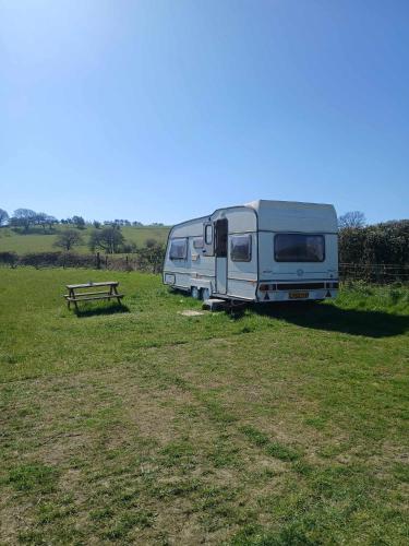 a trailer parked in a field next to a picnic table at Caravan in The Peak District in Holmesfield