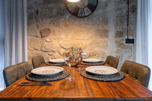 a wooden table with plates and wine glasses and a clock at Lo Raconet d'Arnes in Arnés