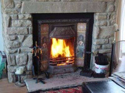 a stone fireplace with a fire in it at Peaceful bliss 200 meters from the beach in Rossnowlagh