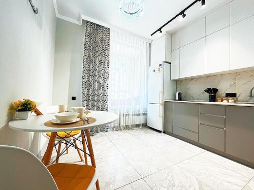 a kitchen with a table and chairs and a refrigerator at Уютная квартира на Левом берегу, ТРЦ Хан Шатыр in Astana