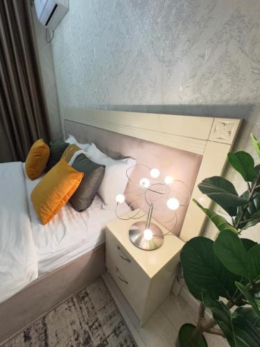 a small bed with pillows and a lamp on a night stand at Your Home Away from Home 213 in Almaty