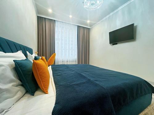 a bedroom with a bed with an orange pillow on it at Уютная квартира на Левом берегу, ТРЦ Хан Шатыр in Astana
