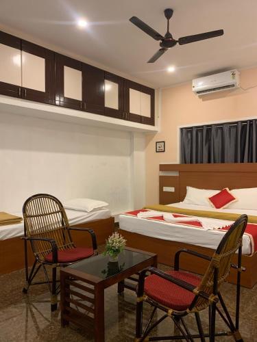a room with two beds and two chairs and a table at Adi Deva Inn in Guruvāyūr