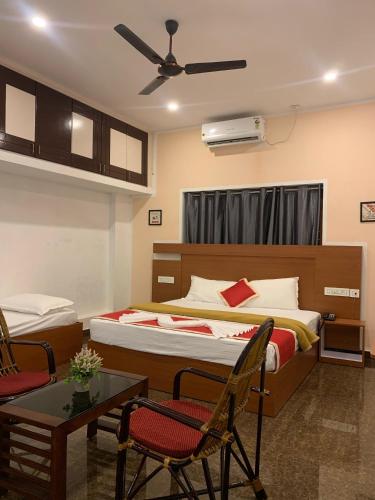 a bedroom with two beds and a table and chairs at Adi Deva Inn in Guruvāyūr