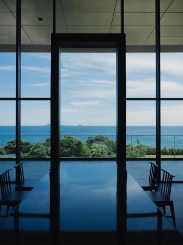 a room with a table and chairs and a view of the ocean at GOTO RETREAT by Onko Chishin in Goto
