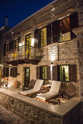 a stone building with lounge chairs in front of it at Halkis Muses in Halki