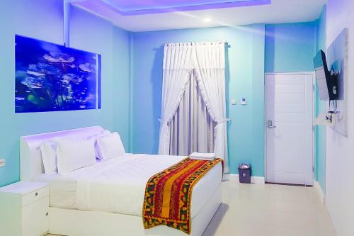a blue bedroom with a white bed and a window at RedDoorz Premium Hotel Sopo Holong Sibolga in Sibolga