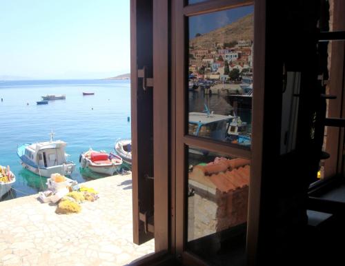 a window view of a harbor with boats in the water at Halkis Muses in Halki