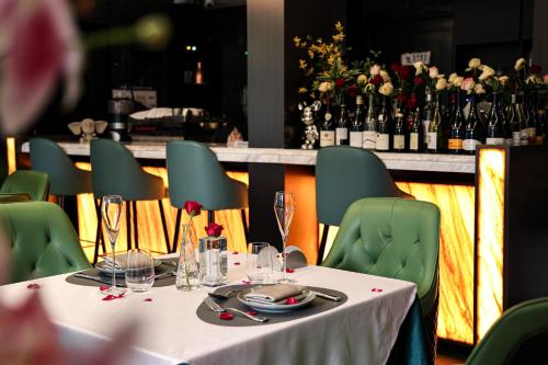 a table with green chairs and a counter with wine bottles at Dak Han Mansion Guangzhou in Guangzhou