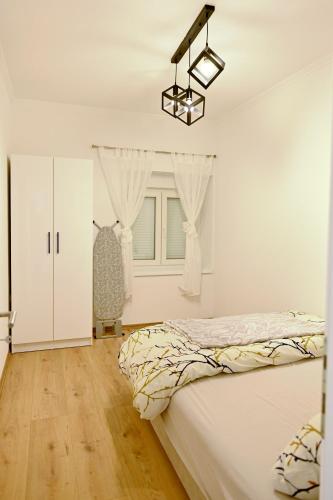 a white bedroom with a bed and a window at Apartman KALINA in Bileća