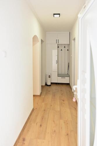 a kitchen with white cabinets and a hard wood floor at Apartman KALINA in Bileća