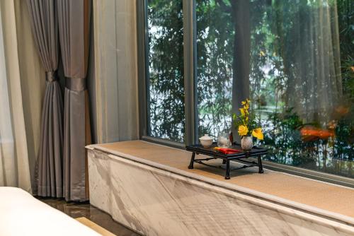 a table on a window sill with flowers on it at Dak Han Mansion Guangzhou in Guangzhou