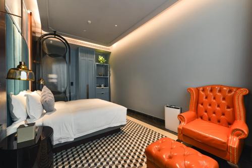 a bedroom with a bed and a red chair at Dak Han Mansion Guangzhou in Guangzhou