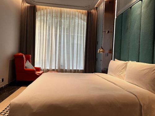 a bedroom with a large white bed and a red chair at Dak Han Mansion Guangzhou in Guangzhou