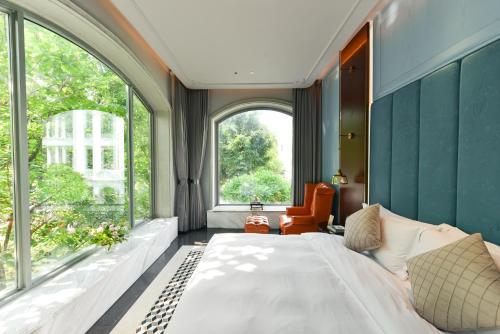 a bedroom with a large bed and large windows at Dak Han Mansion Guangzhou in Guangzhou