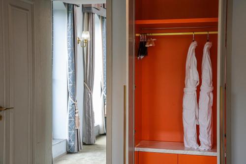 a closet with orange walls and white clothes at Dak Han Mansion Guangzhou in Guangzhou