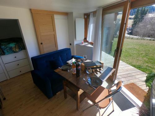 a living room with a table and a blue couch at Jungle room au centre des Carroz in Les Carroz d'Araches