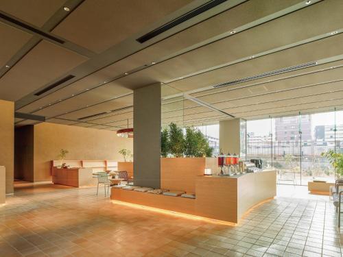 a lobby with tables and chairs in a building at Dorsett by Agora Osaka Sakai in Sakai