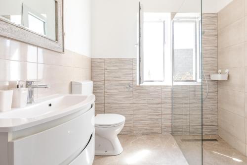 a white bathroom with a toilet and a sink at Naša kuća in Vela Luka