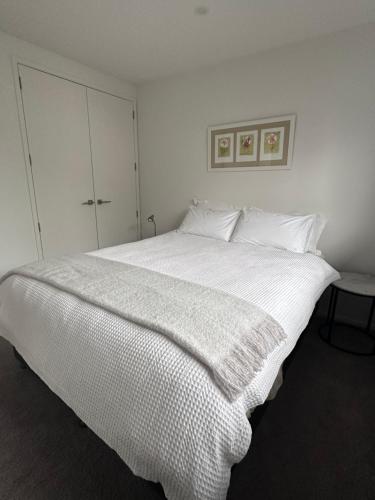 a bedroom with a large bed with white sheets at Easy Beach Holiday in Mount Maunganui