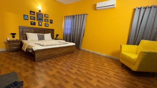a bedroom with yellow walls and a bed and a yellow chair at Hotel Heavenly Stays in Karachi