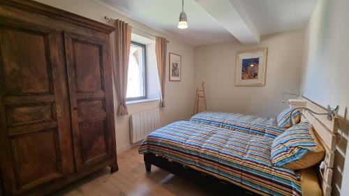 une chambre avec un lit et une armoire en bois dans l'établissement Les Marthalice, à Brégnier-Cordon