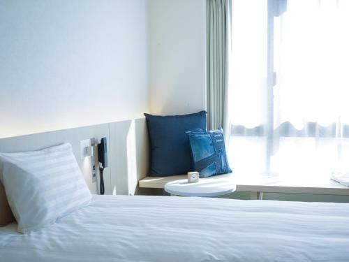 a bedroom with a bed and a chair and a window at Dorsett by Agora Osaka Sakai in Sakai
