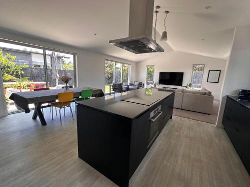 a kitchen and living room with a table and a couch at Easy Beach Holiday in Mount Maunganui