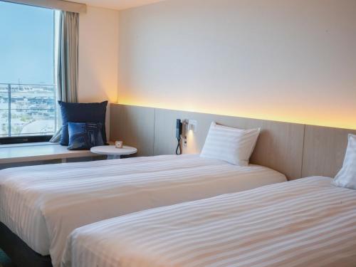 a hotel room with two beds and a window at Dorsett by Agora Osaka Sakai in Sakai