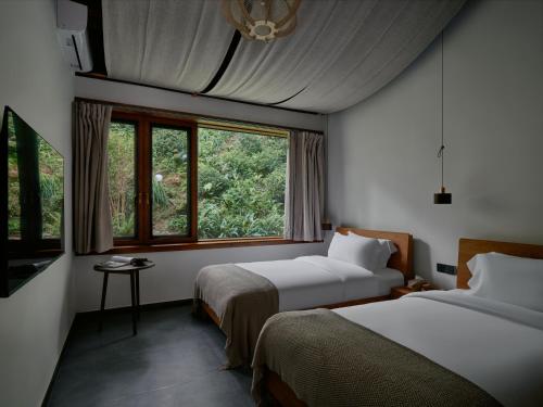 a hotel room with two beds and a window at Jishang Qingcheng Mt Villa in Dujiangyan