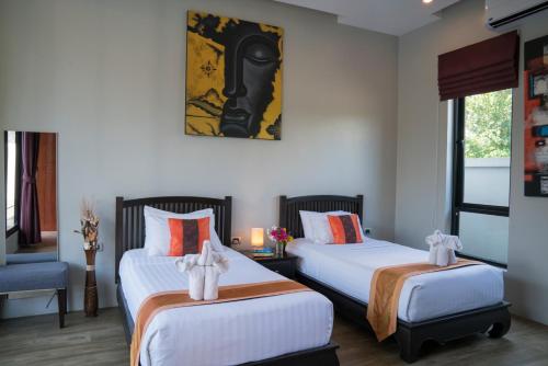 a bedroom with two beds and a picture on the wall at Narintara Private Pool Villas - Free Tuk-Tuk Service to the Beach! in Ao Nang Beach