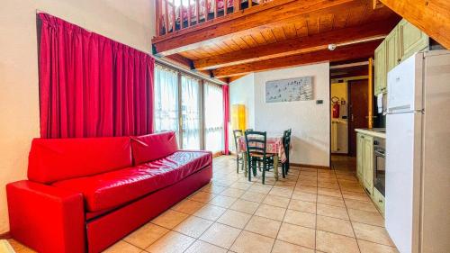 a living room with a red couch and a kitchen at Residence Villa Frejus in Bardonecchia