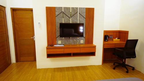 a room with a television and a desk with a chair at BAGUS Guest House in Legian