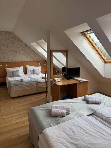 a attic room with two beds and a television at Belvárdi Fogadó in Belvárdgyula