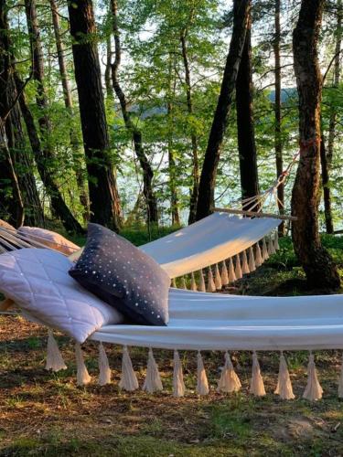 a hammock in the woods with two pillows on it at Caravana Juliana Hobby 545 z widokiem na Jezioro in Swaderki