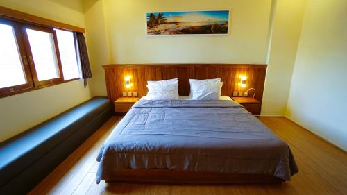 a bedroom with a large bed with two windows at BAGUS Guest House in Legian