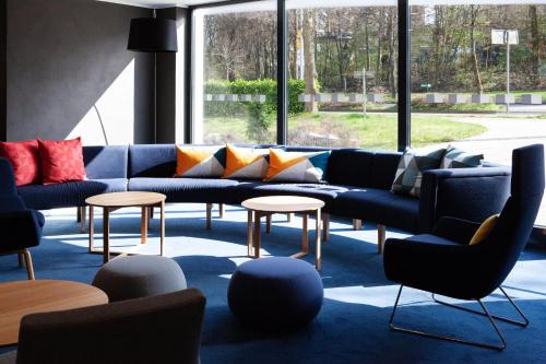 a living room with couches and tables and windows at Holiday Inn Express Neunkirchen by IHG in Neunkirchen