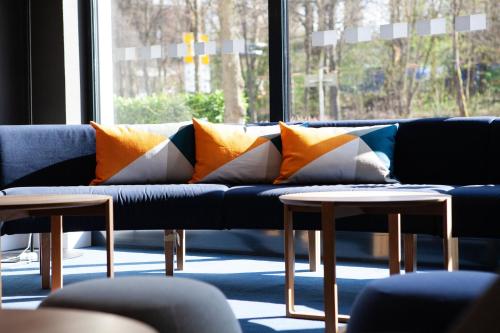a couch with pillows on it in a room with a window at Holiday Inn Express Neunkirchen by IHG in Neunkirchen