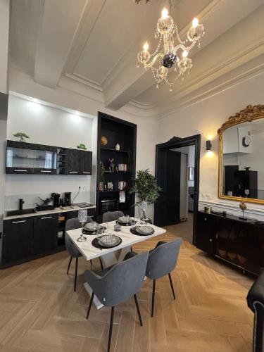 une salle à manger avec une table, des chaises et un lustre dans l'établissement Le petit boudoir de Beziers, à Béziers