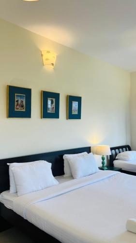 a bedroom with two beds and two pictures on the wall at Sunset Villa in Coonoor