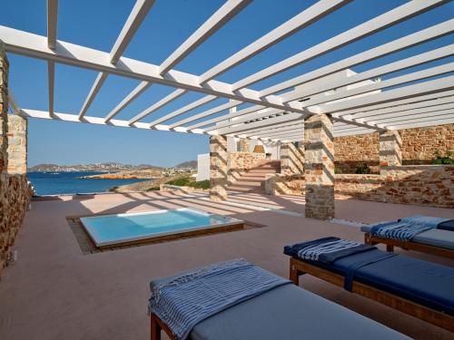 a patio with two beds and a swimming pool at In Paros, fantastic waterfront villa in Parikia