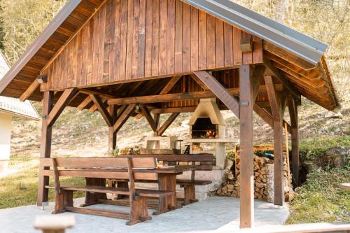 a wooden pavilion with a picnic table and benches at Villa Planica Holiday Home in Kupa