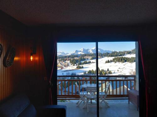 Cette chambre dispose d'un balcon offrant une vue sur une montagne enneigée. dans l'établissement Appartement chalet en plein centre des Saisies, à Hauteluce