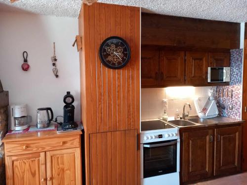 a kitchen with wooden cabinets and a clock on the wall at Appartement chalet en plein centre des Saisies in Hauteluce