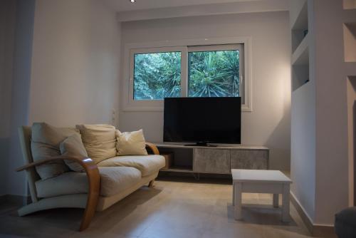 a living room with a couch and a flat screen tv at Garden Villa Patra in Flámbouras