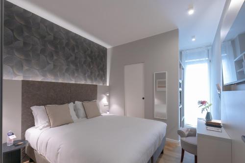 a white bedroom with a large bed and a chair at AH - Duomo Signature in Milan